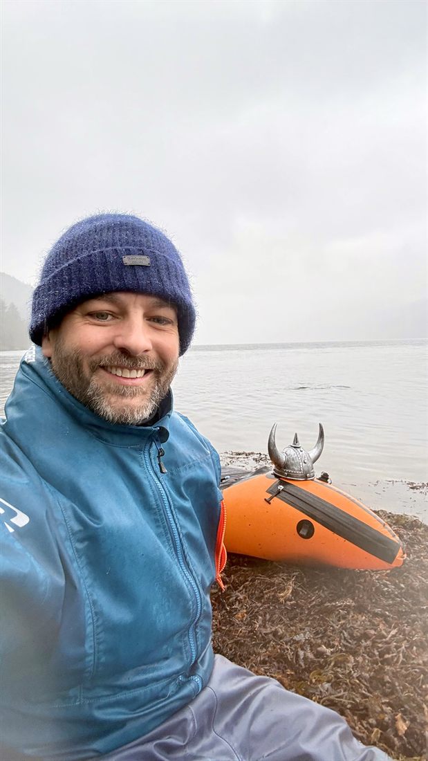 Chris Watson packrafting with a viking helmet.
